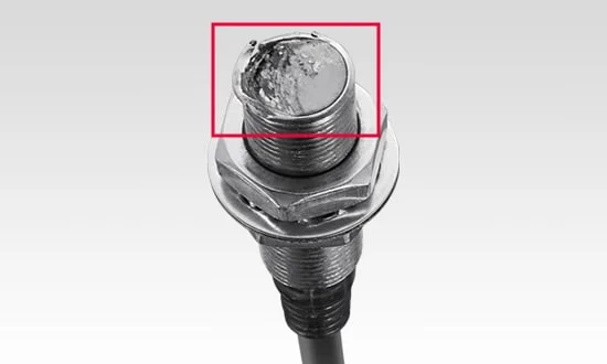 Superficie de detección de plástico de un sensor de proximidad convencional, dañada por el impacto