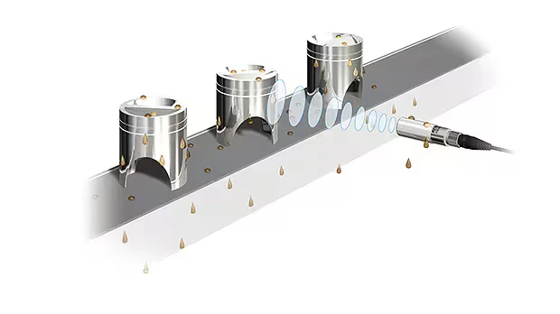 Sensor FW detectando piezas metálicas a través de salpicaduras y gotas sobre una línea de producción